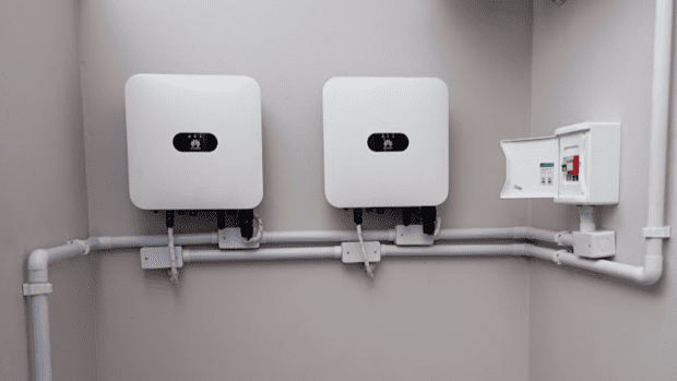 Dois inversores Huawei alinhados em parede cinza, com quadro de proteção e eletrodutos em instalação da TeraSolar
